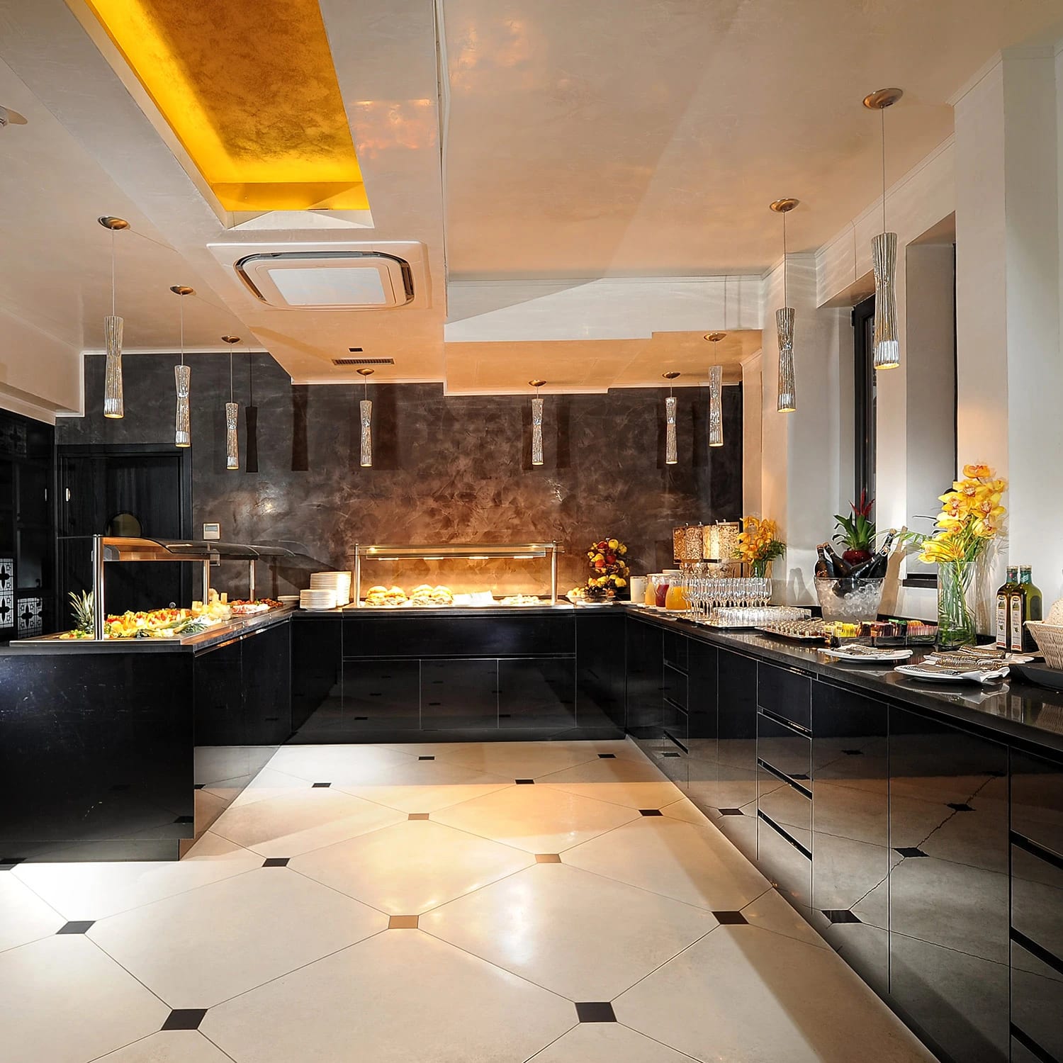 Kitchen with sleek black cabinetry, marble floors and a lit ceiling cove