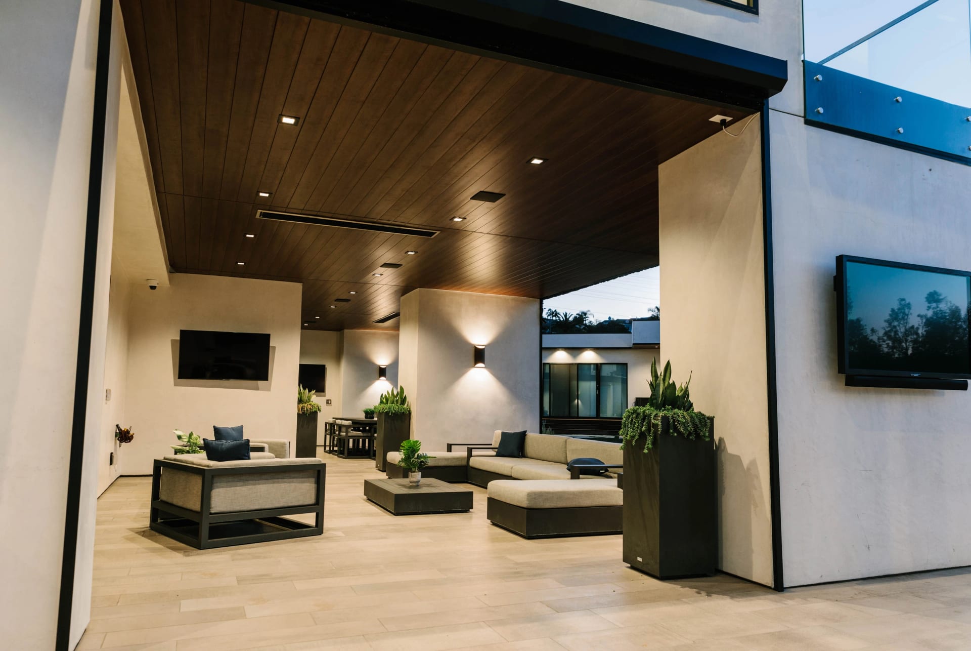 Covered outdoor living room with a wood ceiling, sectional seating and a wall-mounted television