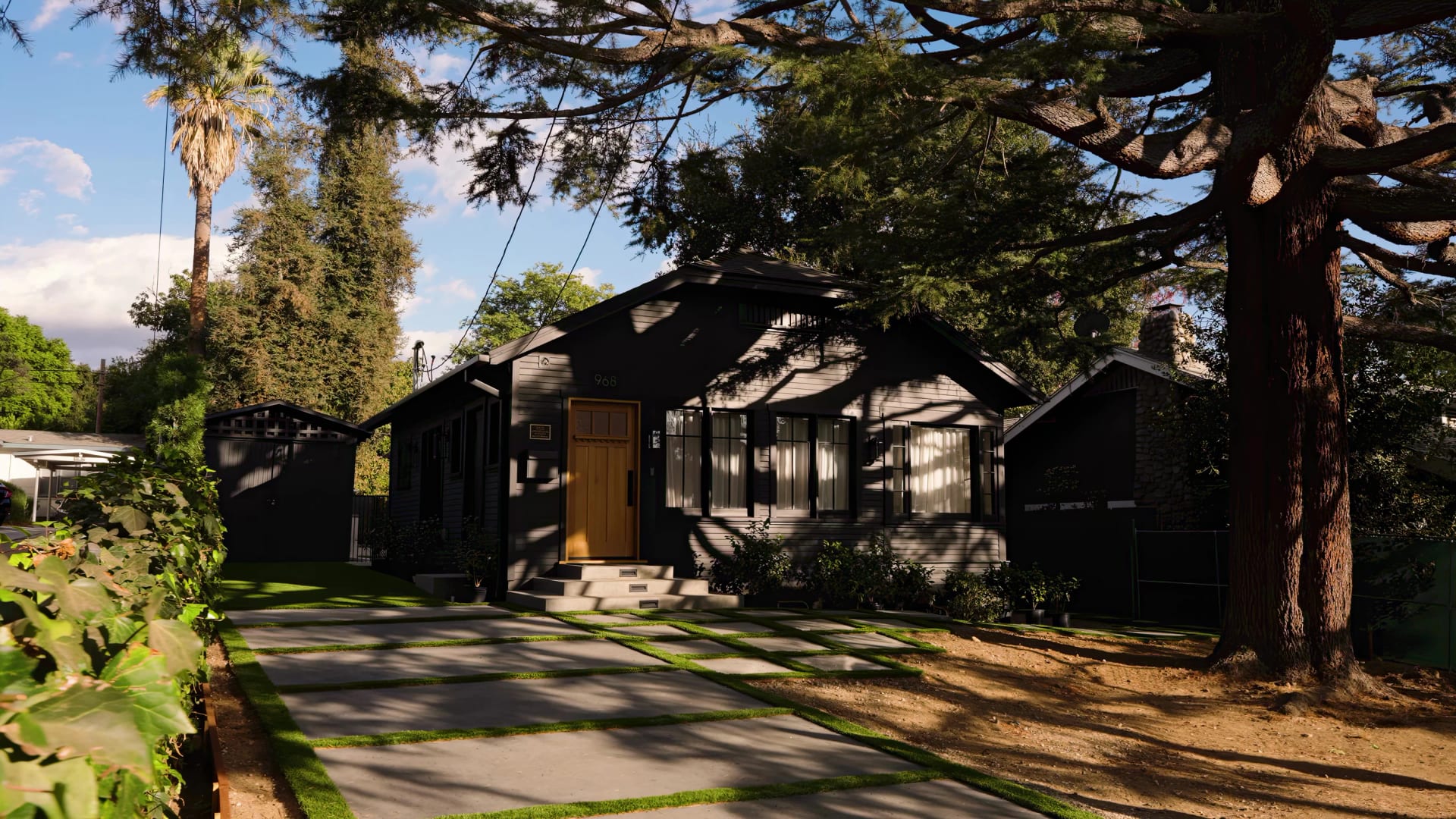 Single-story home with a dark exterior beneath mature trees