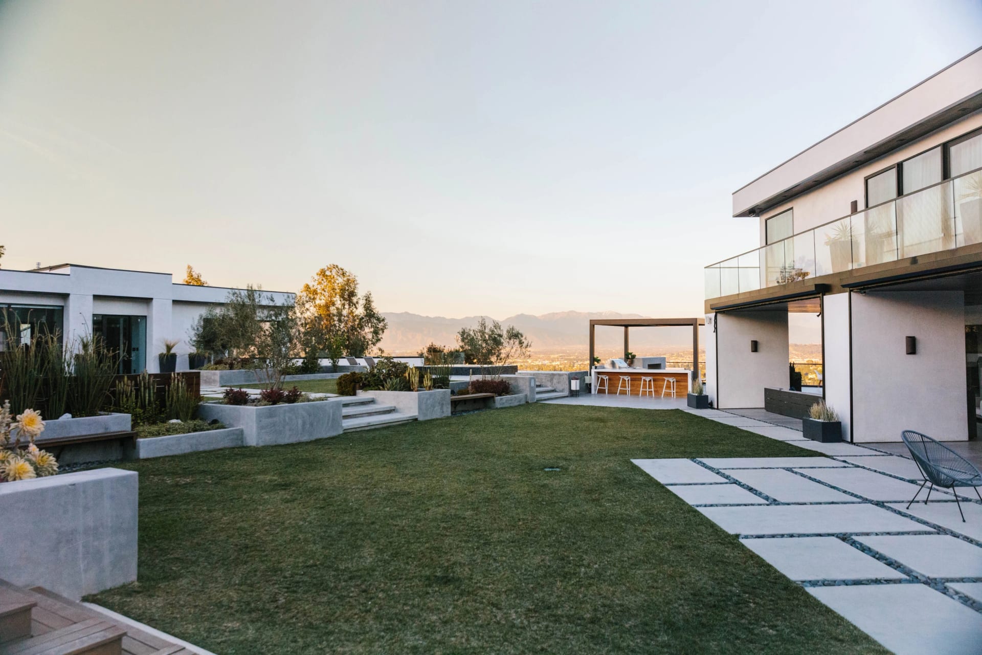 Wide lawn with stepping pavers leading to a modern house with a balcony