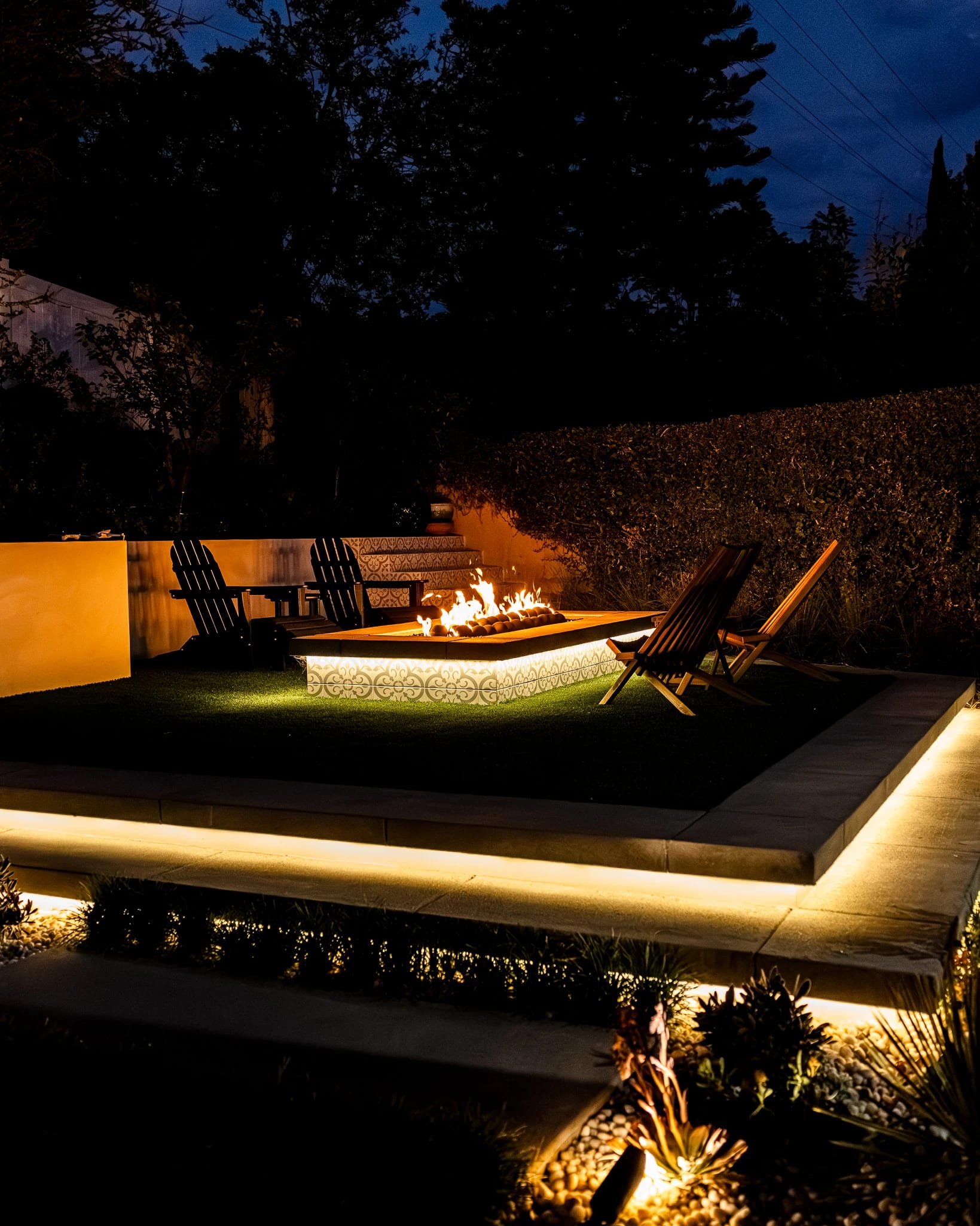 Sunken fire pit lounge with lit steps at night