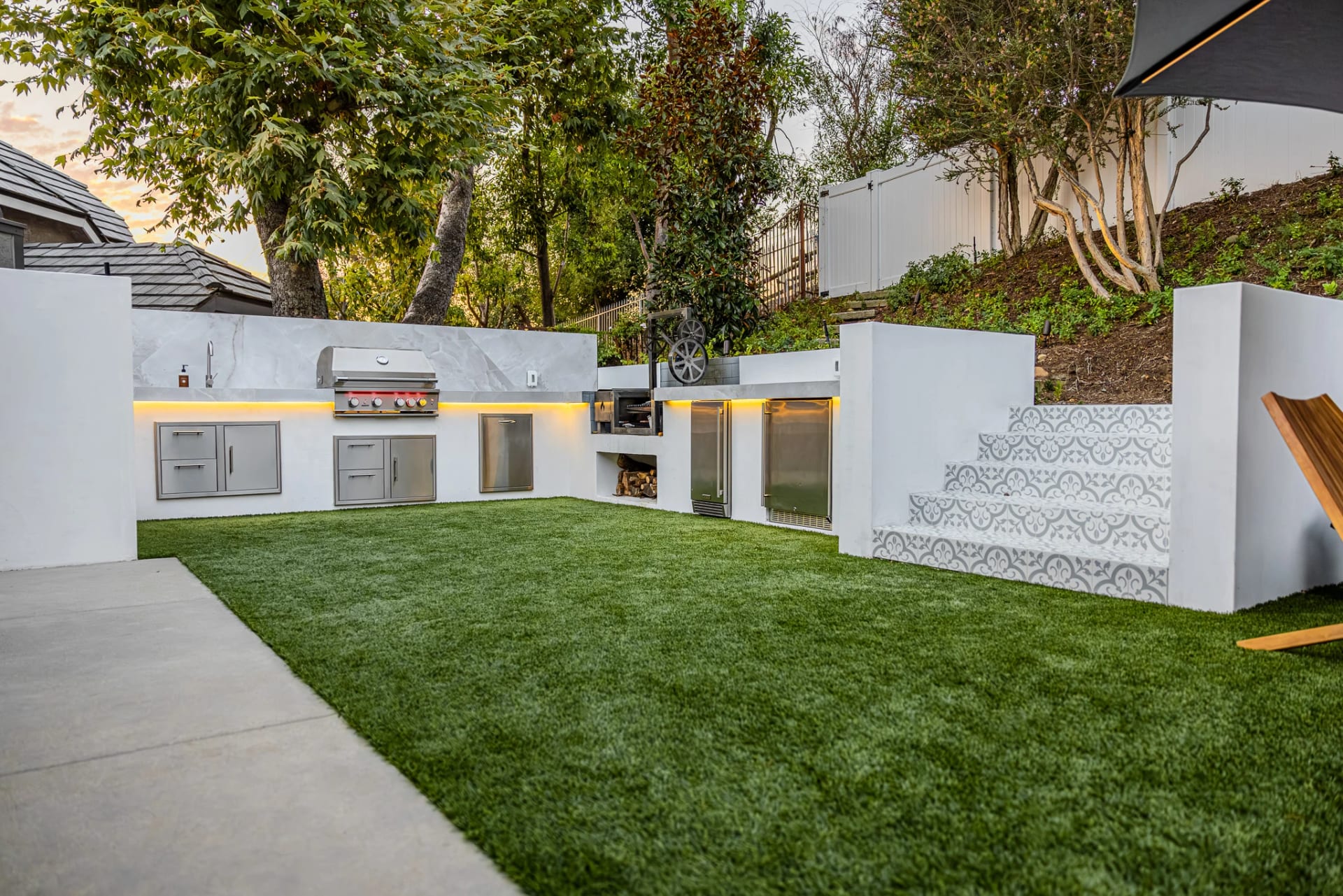 Outdoor kitchen built into a white garden wall with a patterned tile panel