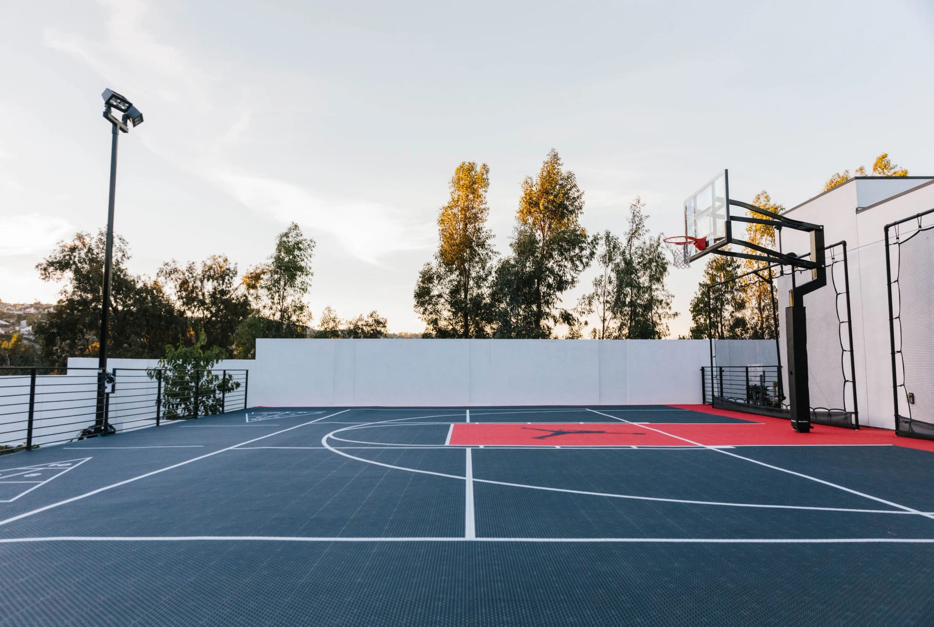 A custom residential basketball court surrounded by white walls and planting