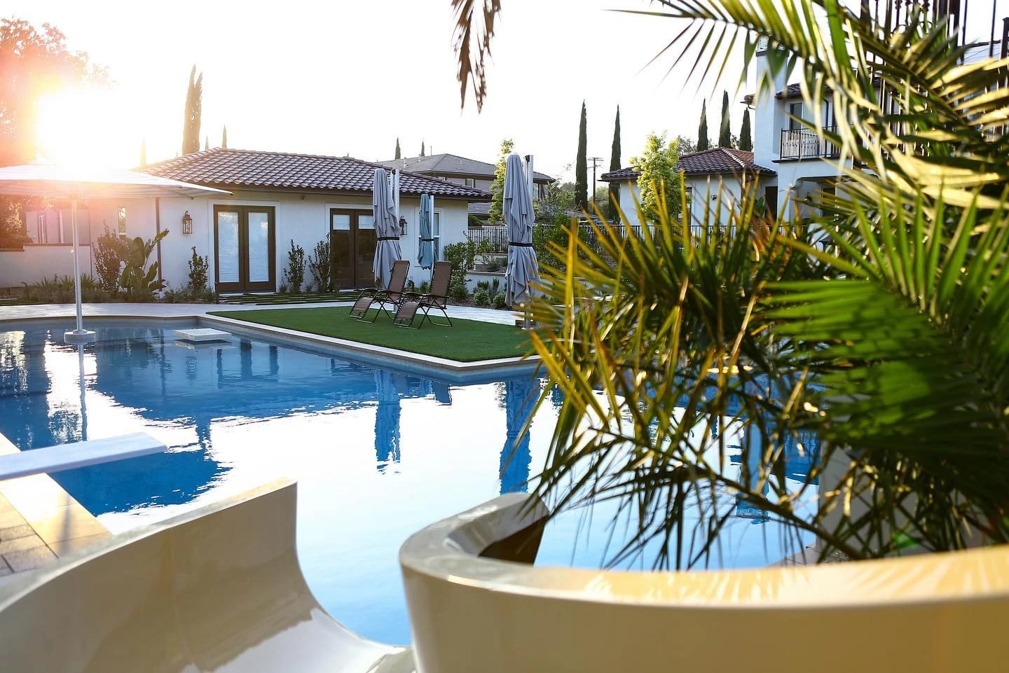Pool and sun deck beside a Mediterranean home at sunset