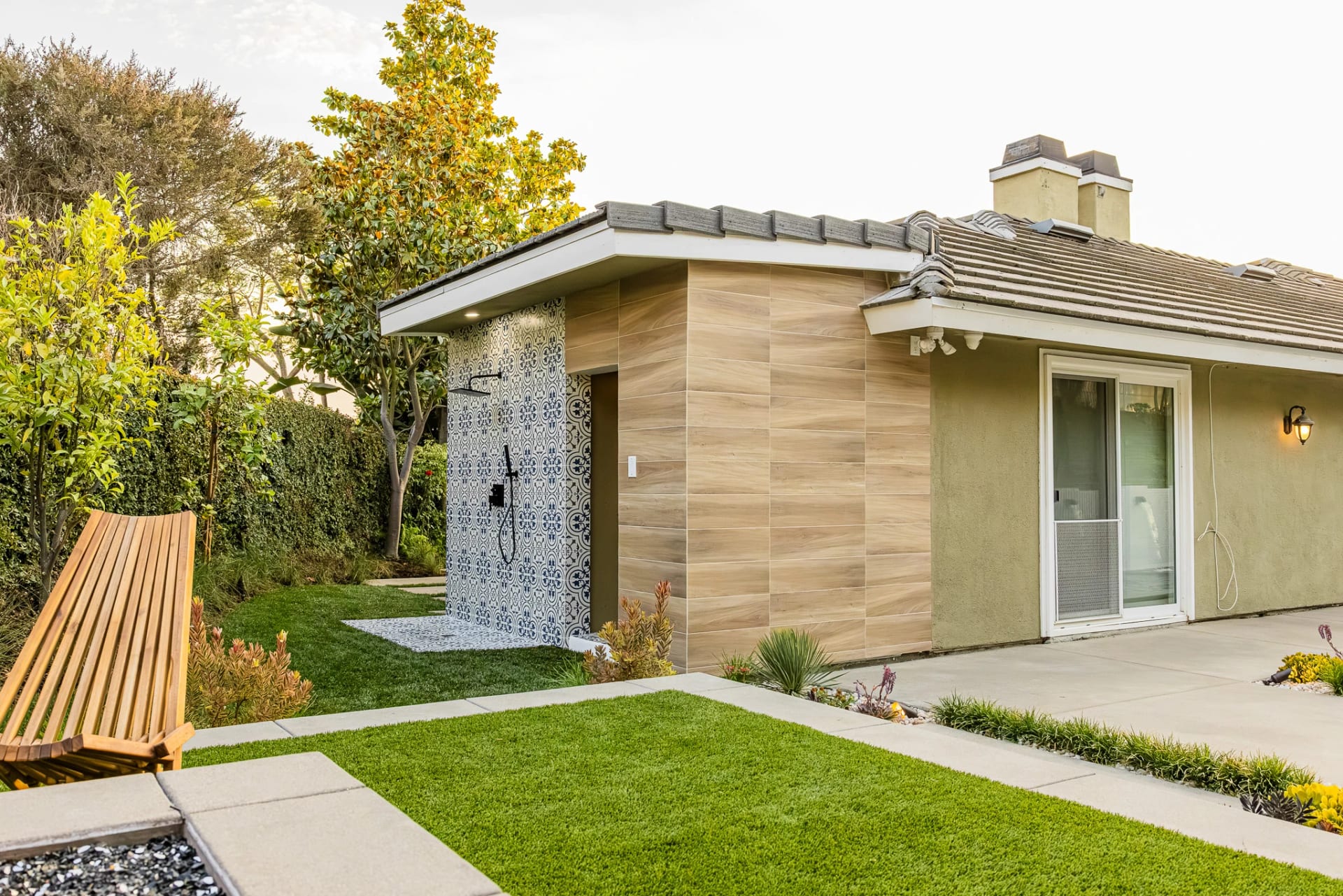 Backyard with a patterned tile wall, wood siding and a lawn