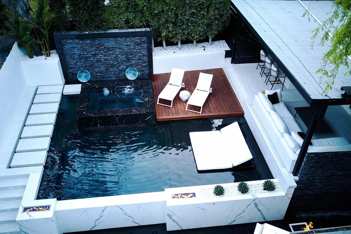 Raised spa with a wooden deck, sun loungers and white lounge seating