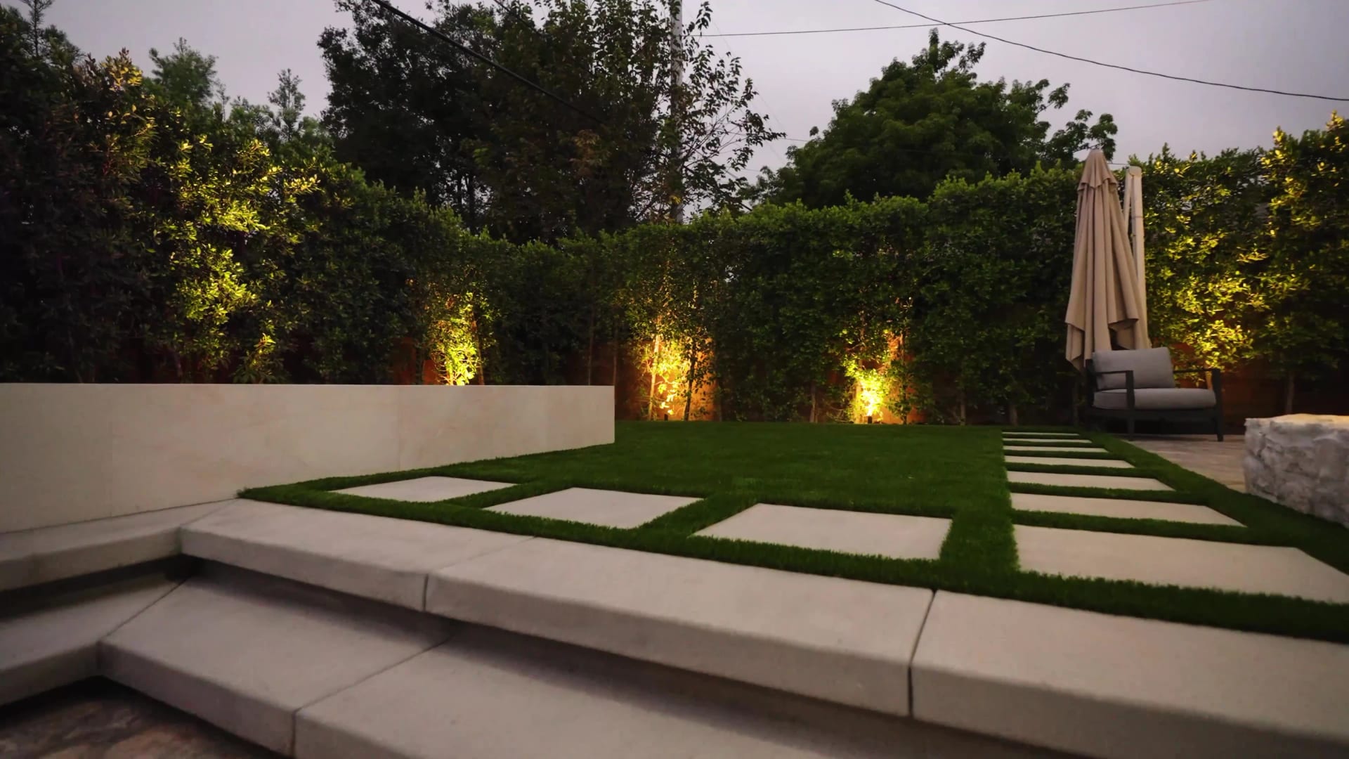 A contemporary garden with geometric paving, sculpted steps, and integrated lighting