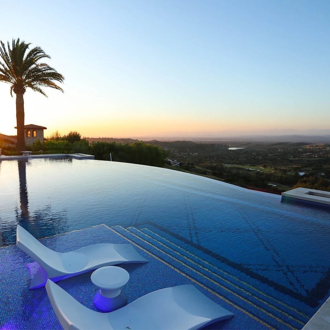 Infinity pool with a spa and built-in sun shelf loungers at sunset