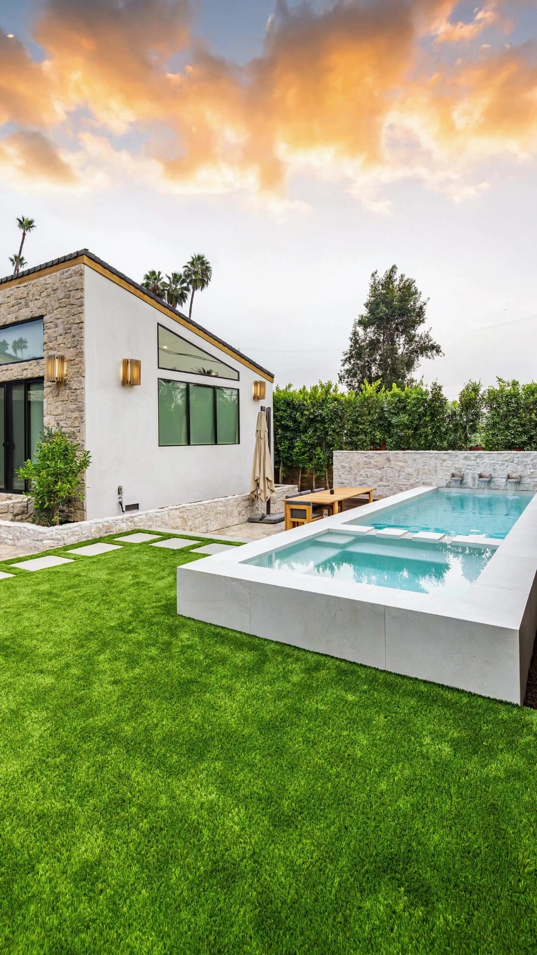 Stone and stucco home with a raised plunge pool at sunset