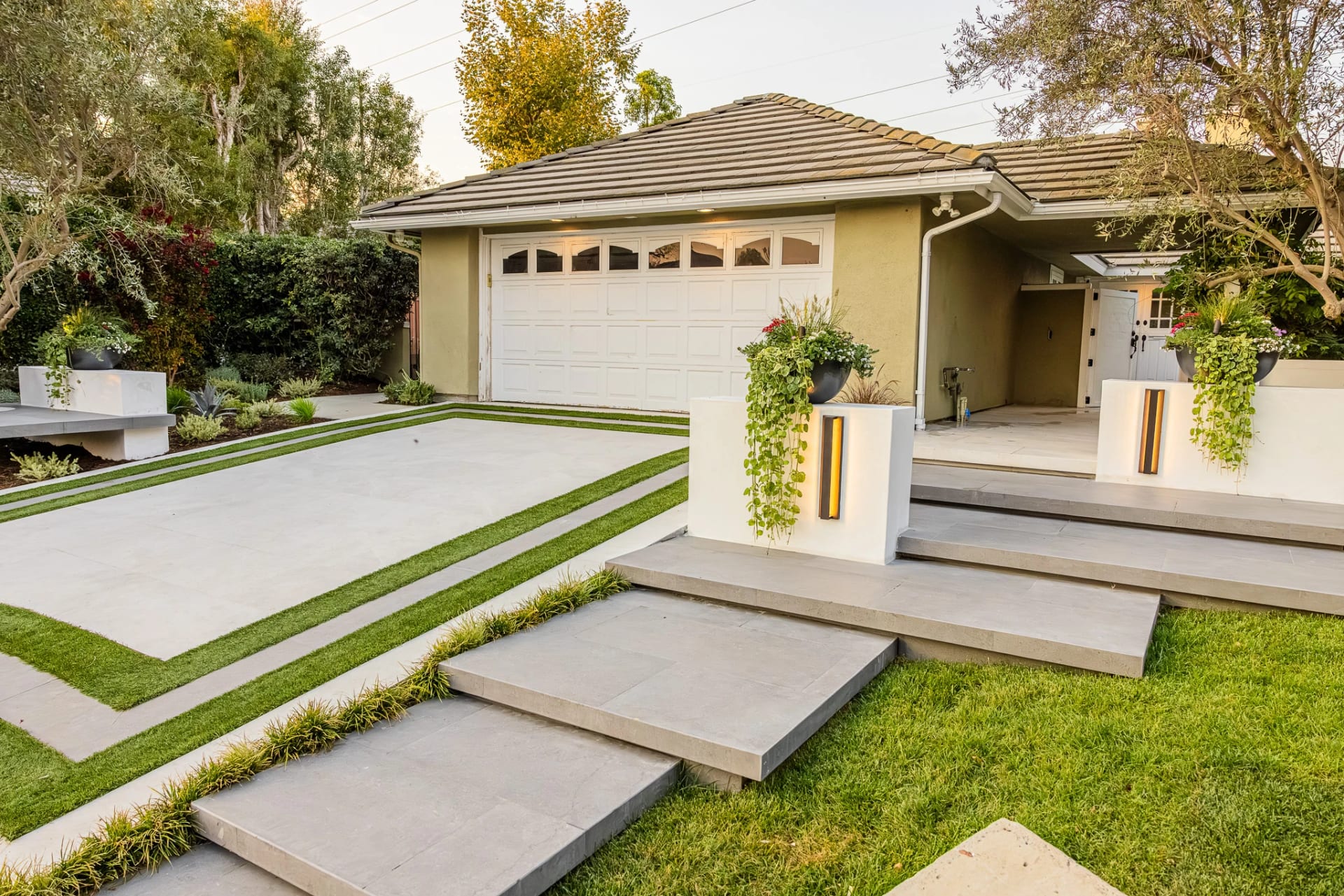 Front walkway of floating concrete steps with lawn strips leading to a garage and entry