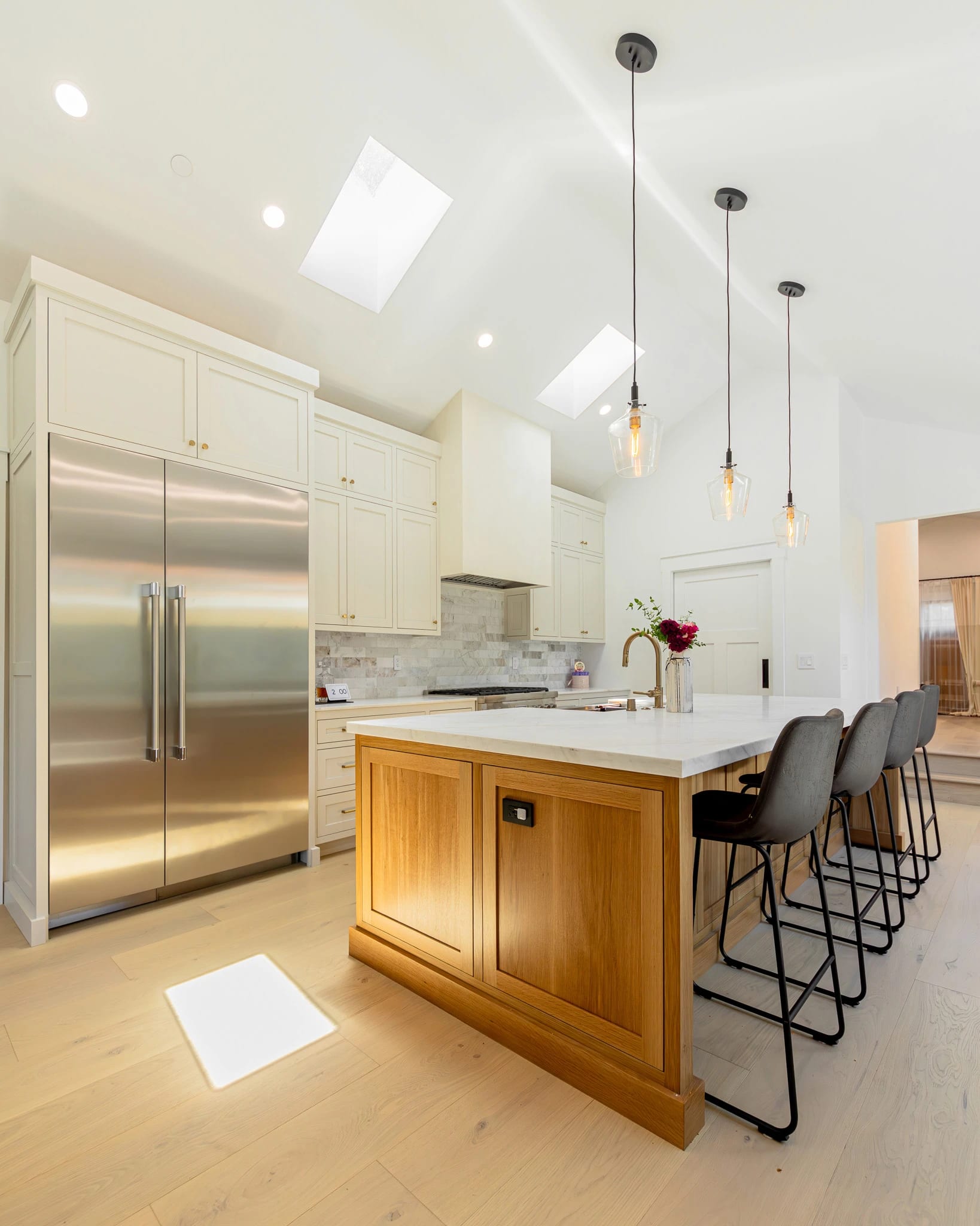 Kitchen with white cabinetry, a wood island and pendant lights under a skylight
