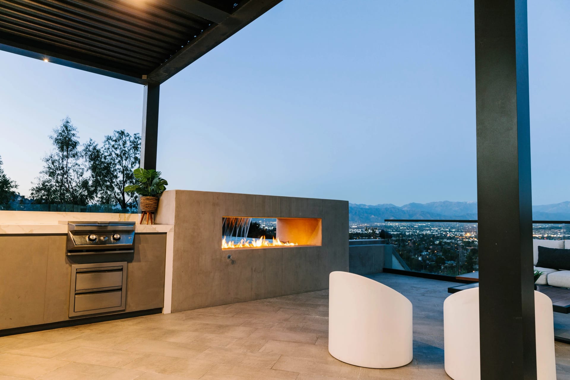 An outdoor kitchen and linear fire feature overlooking the hills