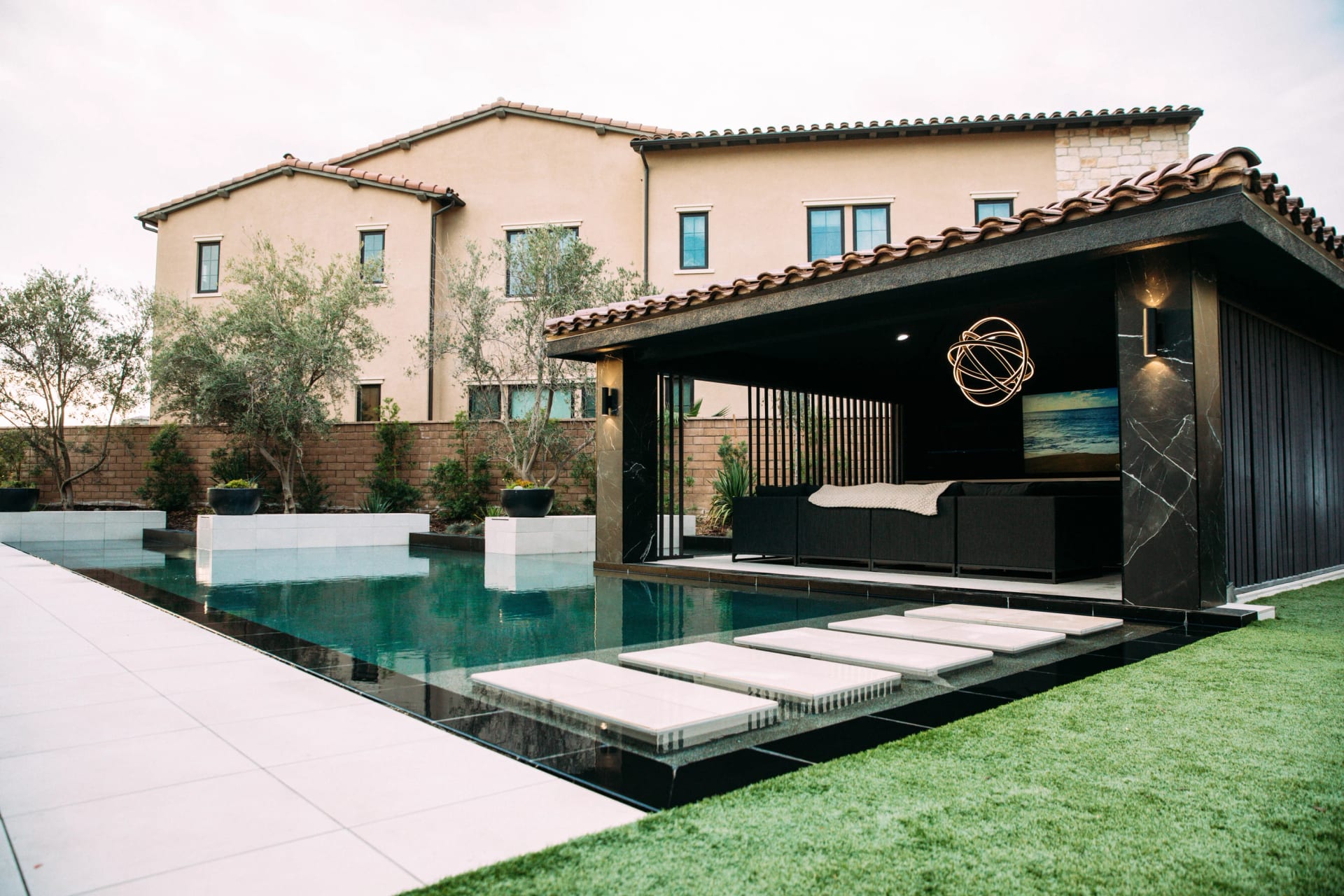 Spanish-style home with a black cabana beside a pool at sunset
